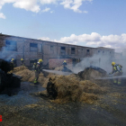 Los Bomberos sofocando el incendio en la balas de paja. 