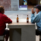 Varias personas se toman una cerveza en un banco de una calle del centro de Barcelona.