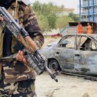 Los talibanes montan guardia cerca de un coche que se usó para disparar cohetes contra el aeropuerto.