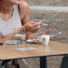 Una mujer fuma un cigarrillo en una terraza