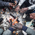 Un grup de migrants s’escalfa en un campament a Calais.