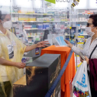 Una dona adquireix un paquet de mascaretes en una farmàcia.