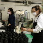 Dos trabajadoras de la cooperativa de Arbeca precintan botellas de aceite.