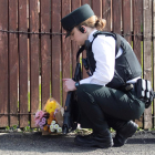 Una policia diposita un ram de flors al lloc del crim.