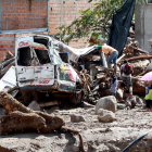 Habitantes del barrio San Miguel observan un vehículo destruido.