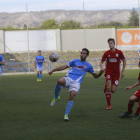 Un jugador del Binéfar controla el balón delante de dos defensas del Caspe.