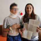 La víctima, ayer, junto a su madre, que muestra la denuncia y el informe de lesiones.