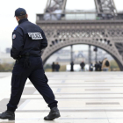 Un agente de policía patrulla frente a la Torre Eiffel.