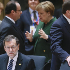 Rajoy sentado mientras Merkel y Hollande charlan antes del inicio de la cumbre.