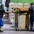Imatge de dos operaris transportant material a la sortida d’una empresa.