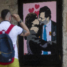 Un artista urbà pinta Rajoy i Puigdemont besant-se a prop de la Generalitat