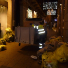 Operarios recogiendo la basura que los comerciantes dejan en las puertas de los comercios del Eix. 