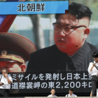 Peatones caminando bajo un monitor que muestra al líder norcoreano Kim Jong-un ayer.