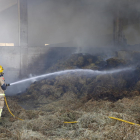 Un bomber apagant ahir l’incendi a l’interior de la granja.