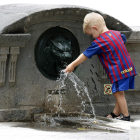 Un nen juga amb l'aigua d'una font.