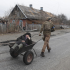 Un soldado ucraniano lleva a una mujer en un carro.