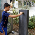Dos nens obrint una font d'aigua en una plaça de Mollerussa.