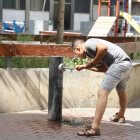 Un home es refresca en una font a Lleida.