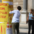 El autor cuelga uno de los carteles ante la mirada de Patrícia Plaja. 