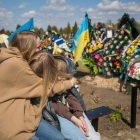 Dos mujeres ucranianas se abrazan ante la tumba de un familiar ayer en motivo del día de los muertos. 