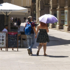 Una pareja se cubre del sol cerca de la plaza Sant Joan.