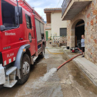 Un camión de bomberos achicando agua de uno de los bajos de una casa de Oliana.