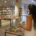 Una lectora fulleja diferents opcions literàries a la llibreria La Fatal, a Lleida.
