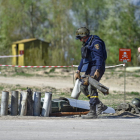Dos soldats ucraïnesos marxen al costat de les restes de projectils detonats.