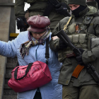Un soldat ajuda una dona que baixa unes escales a Lviv.