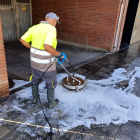 Un operari neteja amb aigua a pressió un carrer de la ciutat.