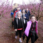 Els assistents a la ruta guiada pels arbres florits i escenaris de la pel·lícula 'Alcarràs' caminant per una finca de fruiters a Massalcoreig