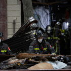 Un grupo de bomberos recoge escombros en el exterior del local donde se registró la explosión.