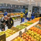 Varios compradores en la sección de frutería de un supermercado.