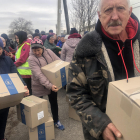 Varias personas recogiendo las cajas que les entrega el reparto de la ayuda humanitaria en Hnilytsia.