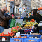 Unos clientes mayores comprando fruta y verdura en una parada.