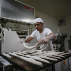 Un trabajador prepara barras de pan en el obrador.