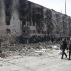 Residentes de Mariupol caminan entre edificios atacados por las tropas rusas.