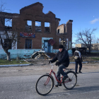Un home amb bicicleta circula pel devastat llogaret ucraïnès de Yatskivka.