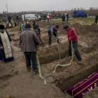 Diverses persones enterren un cos al cementiri de Butxa, a prop de Kíiv.