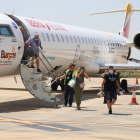 Passatgers del vol que va arribar a Alguaire des de Menorca ahir al migdia i, a la imatge de la dreta, demostració de drons a les instal·lacions de l’aeroport.