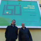 El alcalde de Mollerussa, Marc Solsona, y el director de Fira de Mollerussa, Xavier Roure, posan delante de la valla con el cartel de la 150 Fira de Sant Josep, delante de los pabellones feriales.