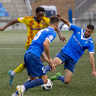 El davanter del Lleida Alpha Bagayoko intenta avançar amb la pilota controlada entre dos jugadors del Badalona.