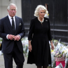 El rei Carles III i Camila, la reina consort, miren els tributs florals deixats fora del Palau de Buckingham aquest divendres.