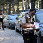 Una pareja de guardas rurales multando varios vehículos a una pista forestal de Riu de Cerdanya