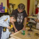 Dos alumnos aprenden nociones de carpintería de la mano de un vecino del Secà. 