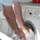 Un home introdueix roba en una rentadora domèstica.