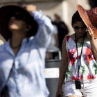 Turistas se tapan del sol durante la última ola de calor.