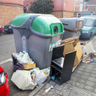 Dos contenedores de Lleida ciudad rodeados de varias bolsas de basura y mobiliario en mal estado. 