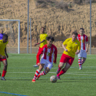 Un jugador local conduce el balón perseguido por un rival.