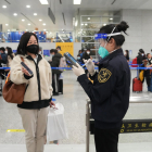 Un treballador de l’aeroport de Pequín revisa la documentació d’una viatgera diumenge passat.